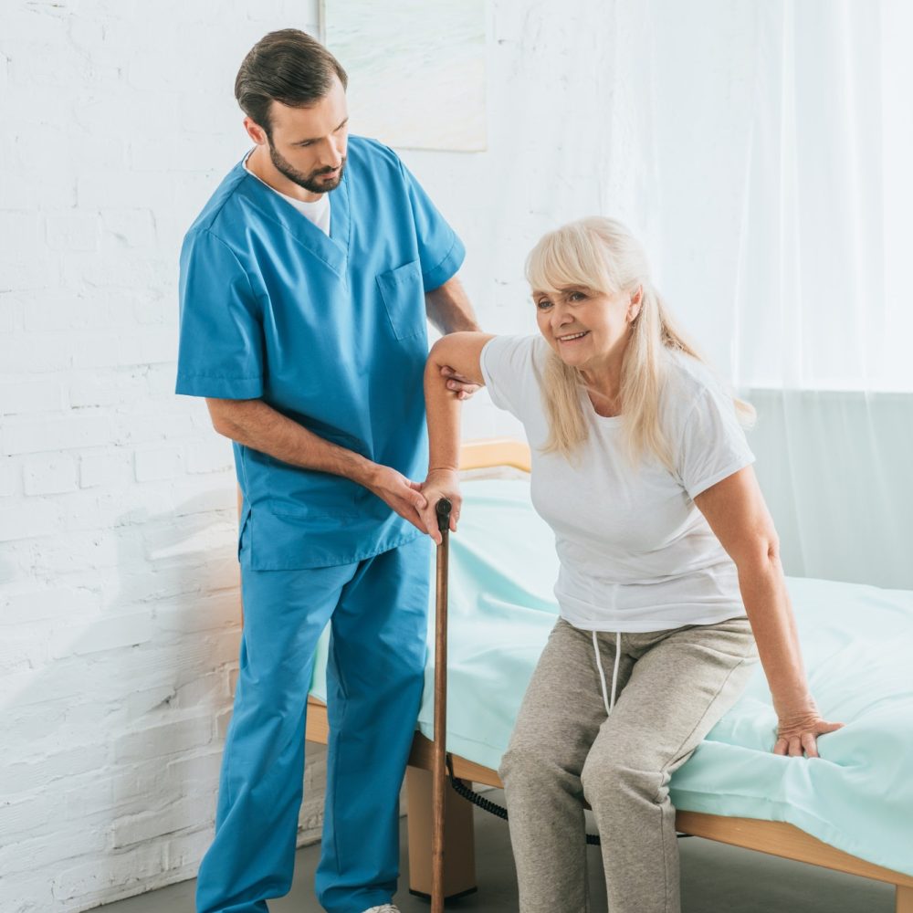 male-nurse-helping-senior-woman-with-walking-stick.jpg